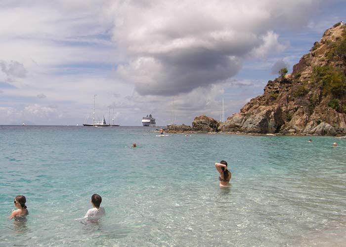 swimming beach scene with a cruise ship in the background