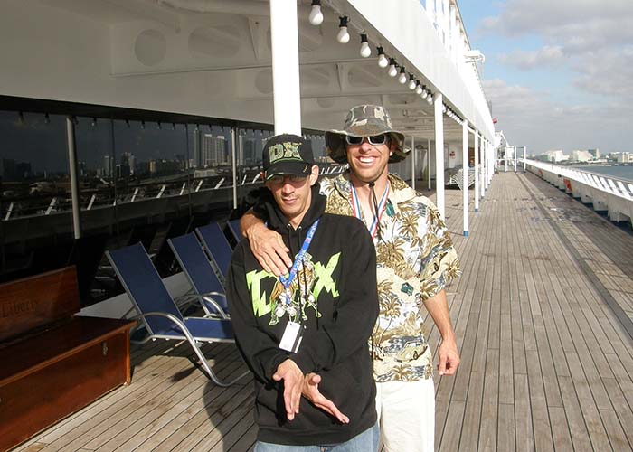 two guys posing on the deck of a cruise ship smiling